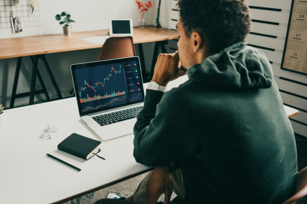 Mann analysiert Aktien- und Kursdiagramme auf einem Laptop am Schreibtisch